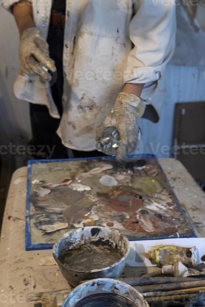 art workshop, messy objects, brushes, paint all mixed up disorganized, woman artist photo