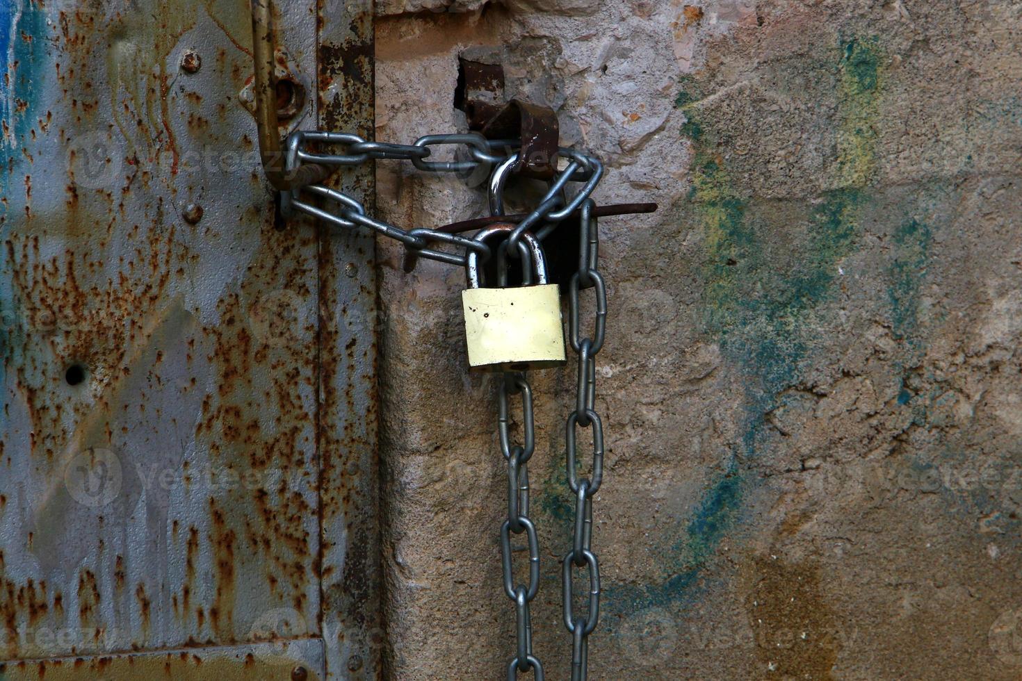 A rusty padlock hangs on a closed gate. photo