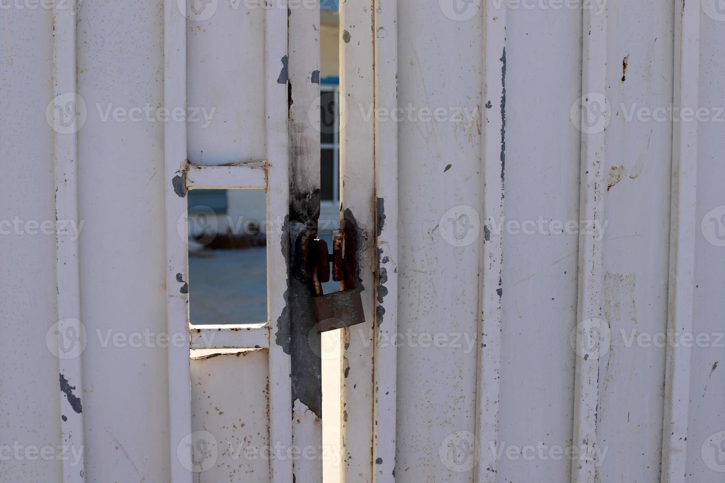 A rusty padlock hangs on a closed gate. photo