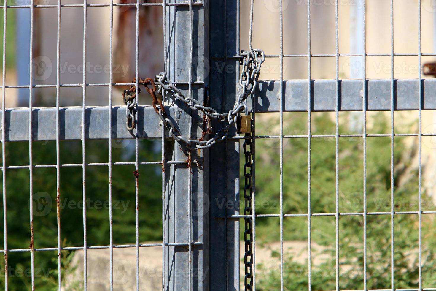 A rusty padlock hangs on a closed gate. photo