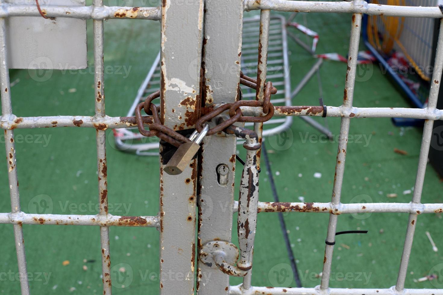 A rusty padlock hangs on a closed gate. photo