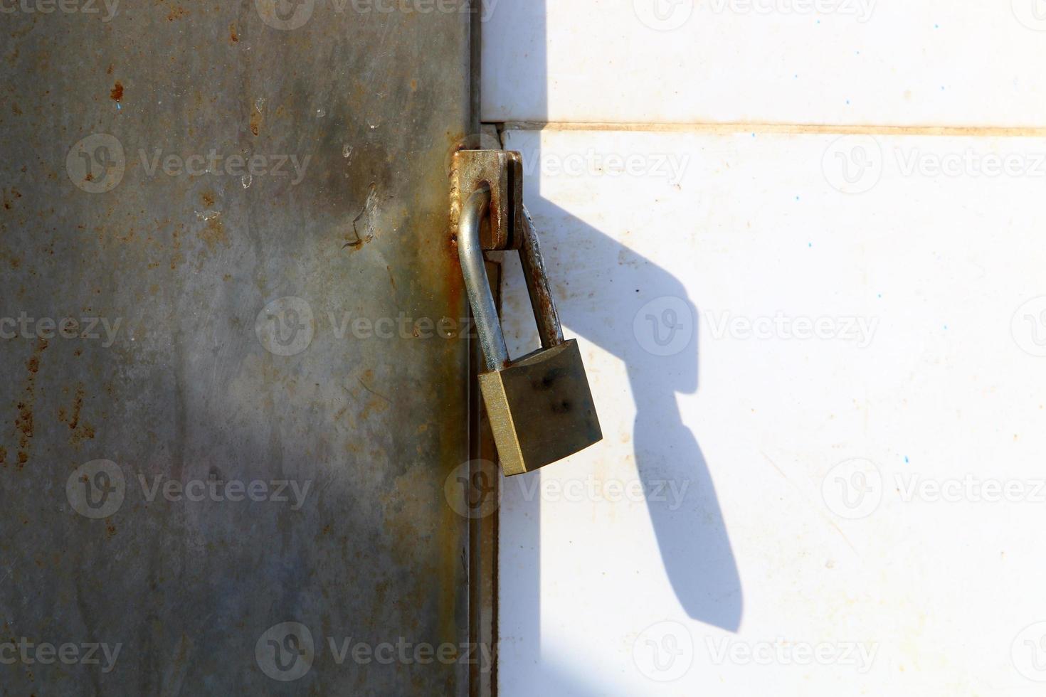 A rusty padlock hangs on a closed gate. photo