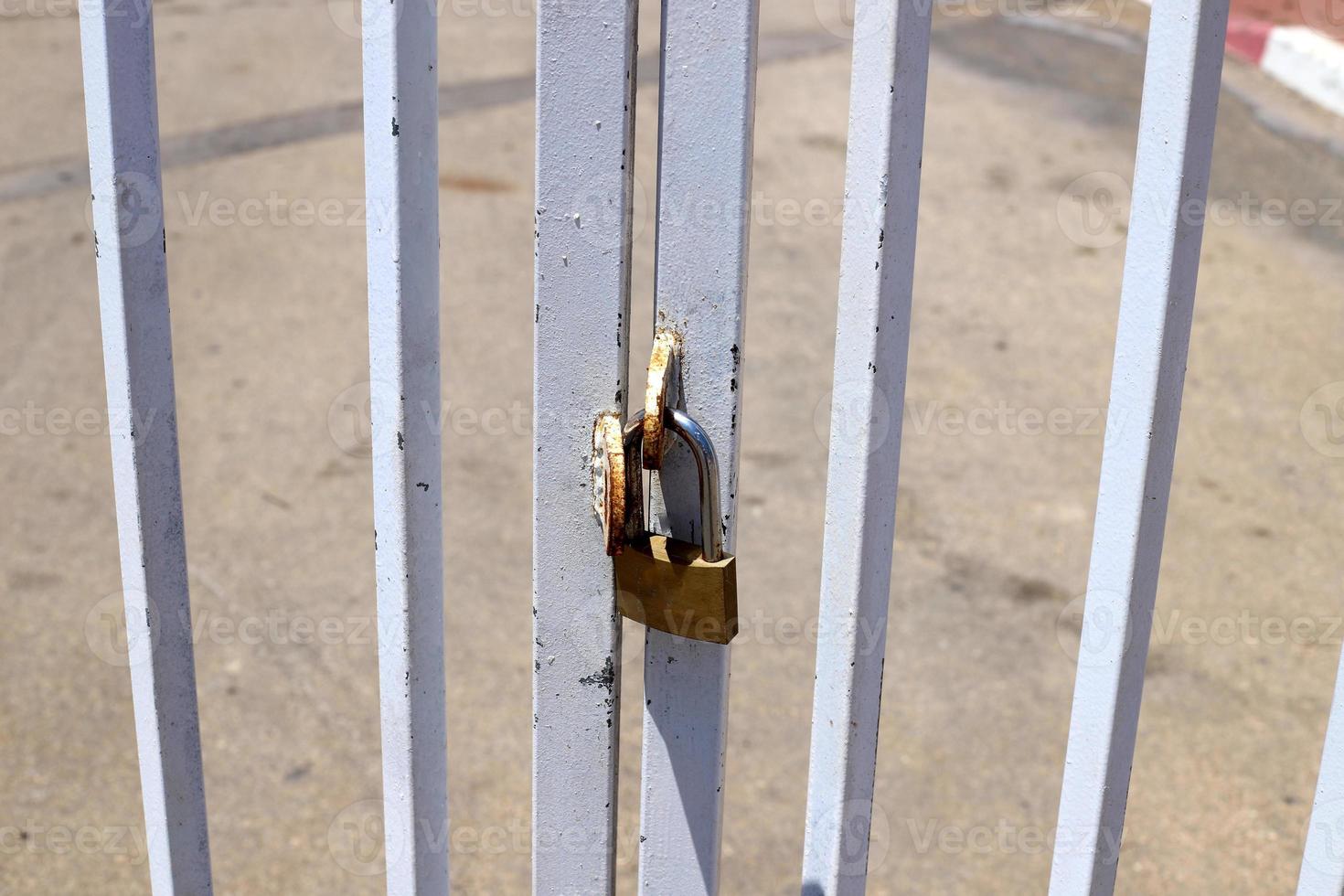 A rusty padlock hangs on a closed gate. photo