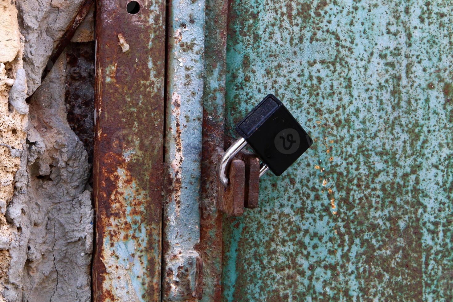 A rusty padlock hangs on a closed gate. photo