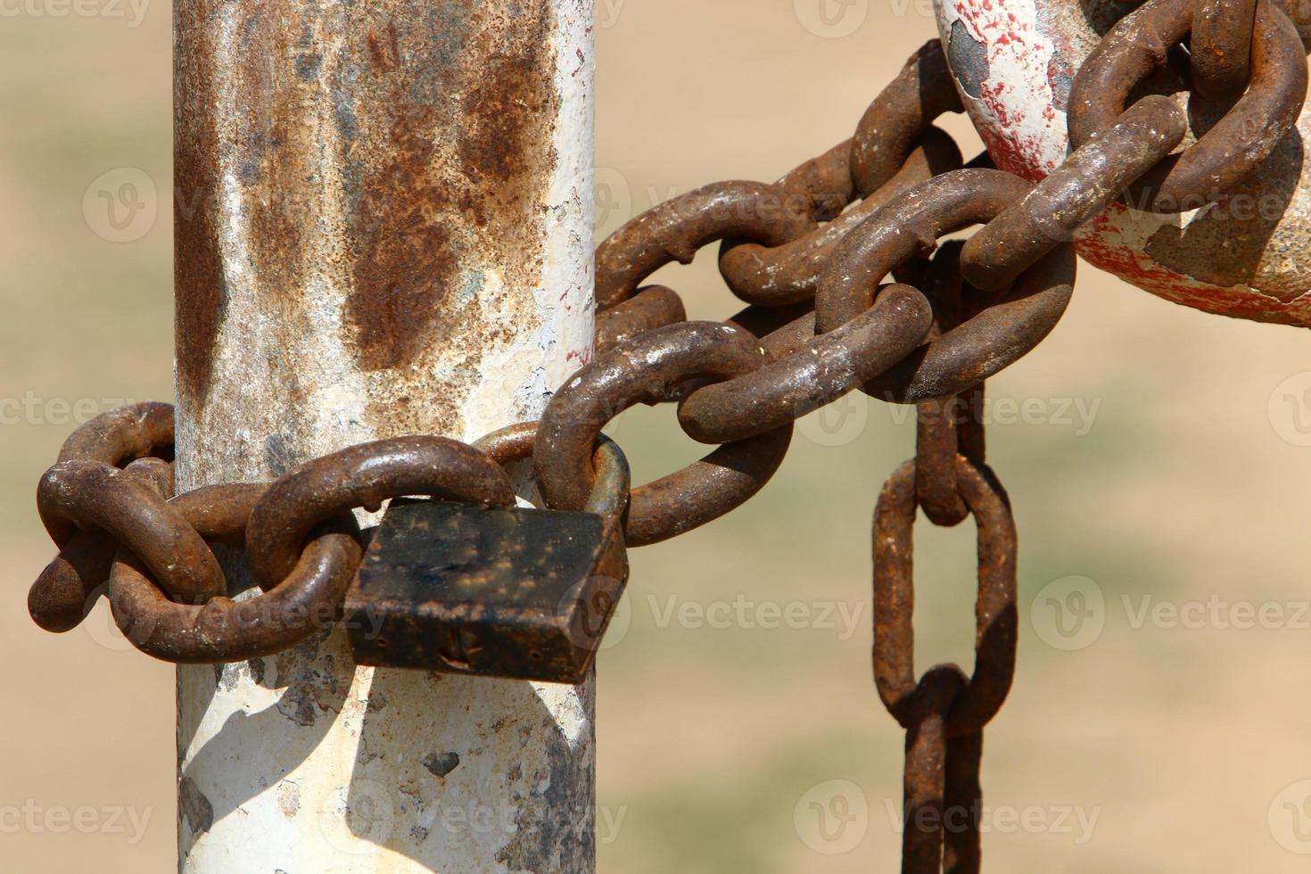 A rusty padlock hangs on a closed gate. photo