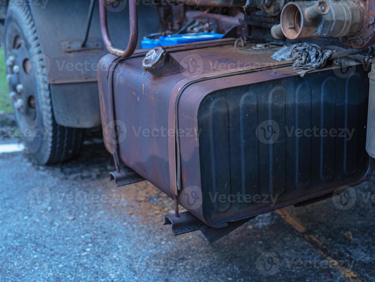 A large oil tank is attached to the side of an old, rusty car. photo