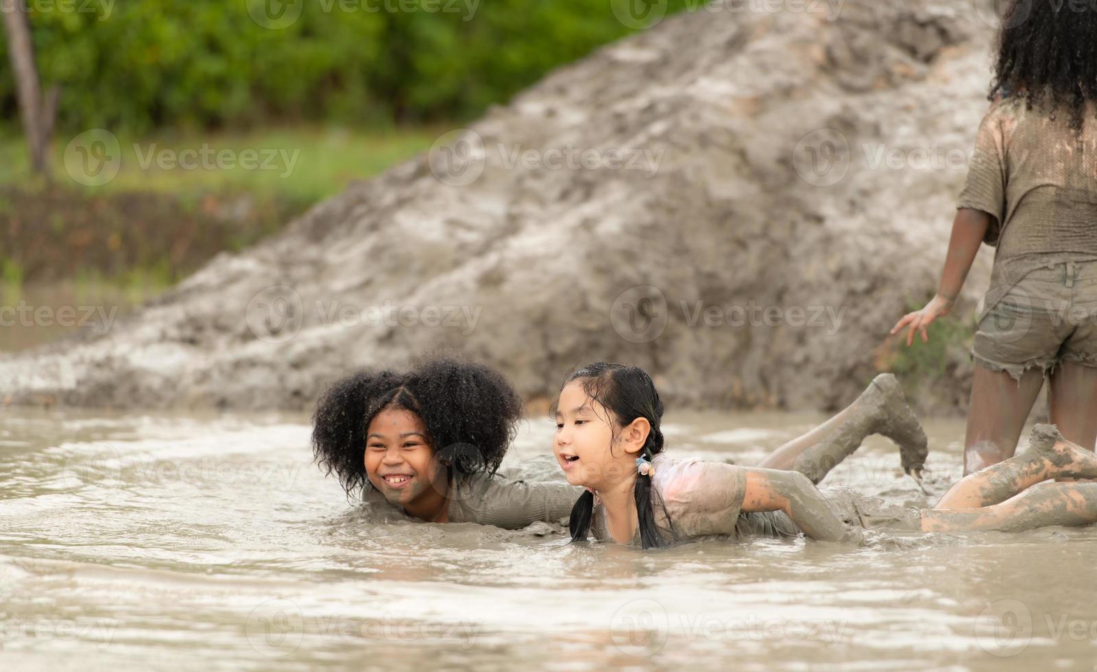 Little girls have fun playing in the mud in the community fields photo