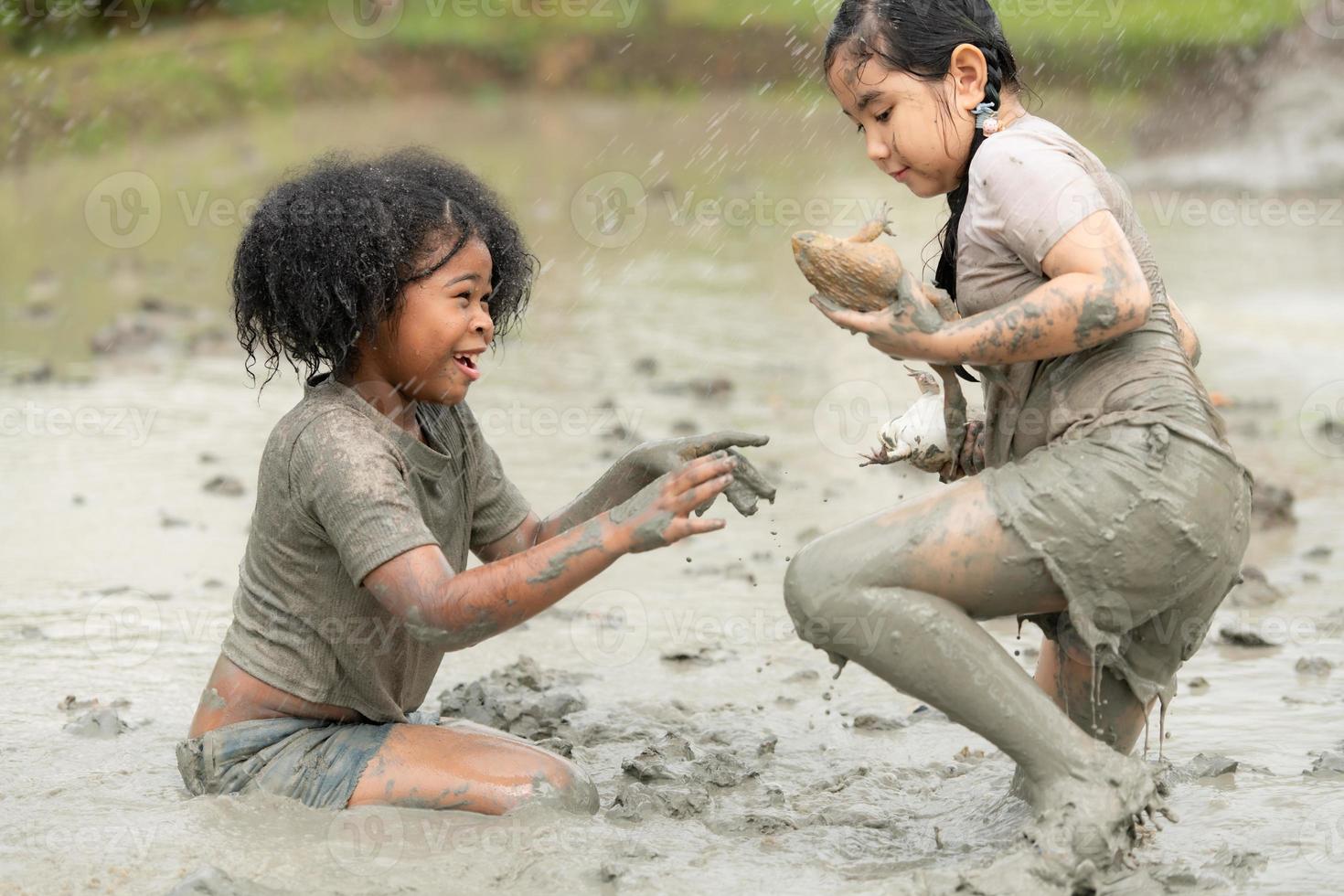 Children have fun playing in the mud in the community fields and catching a frog in a muddy field. photo