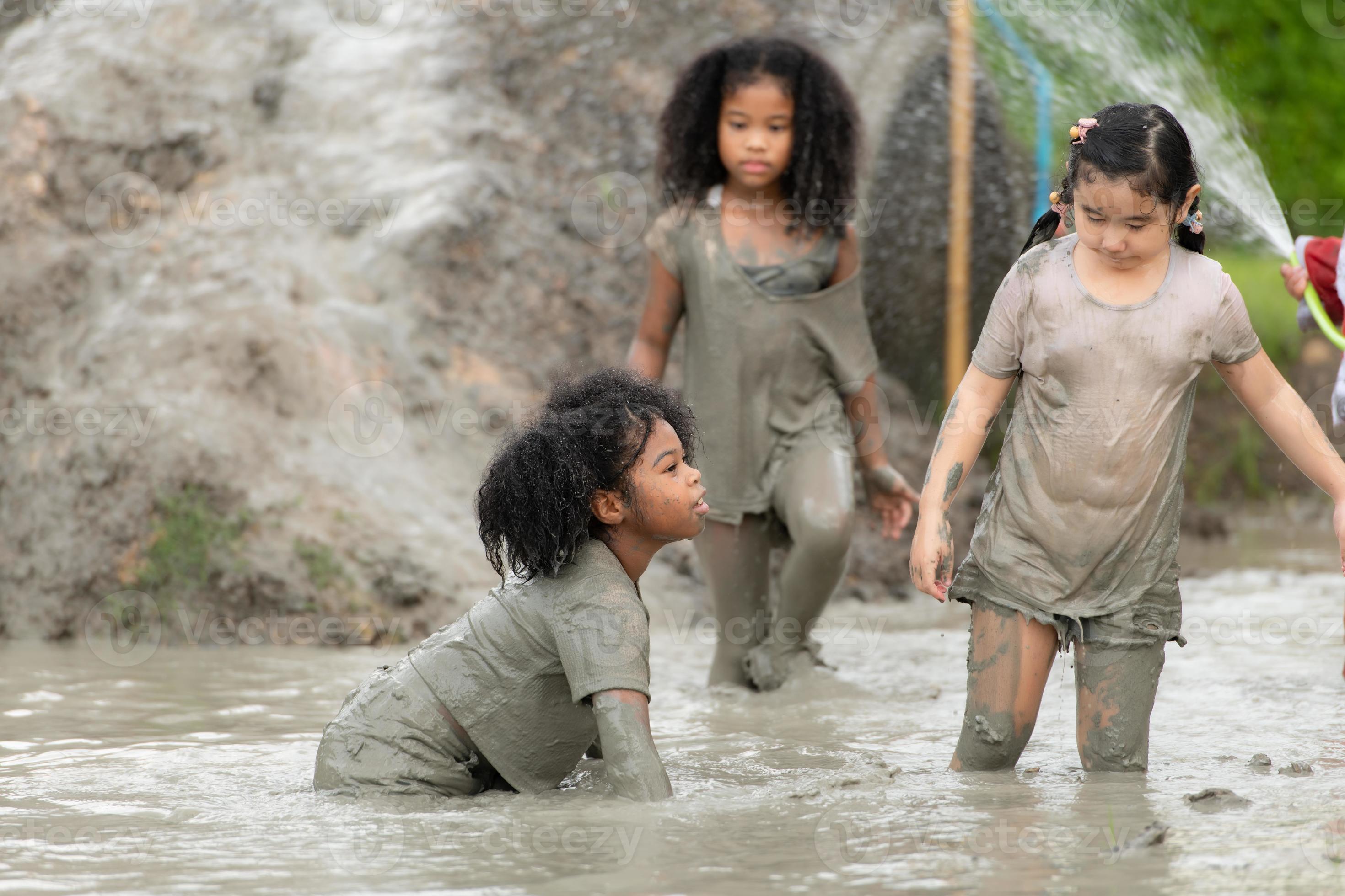 Little girls have fun playing in the mud in the community fields