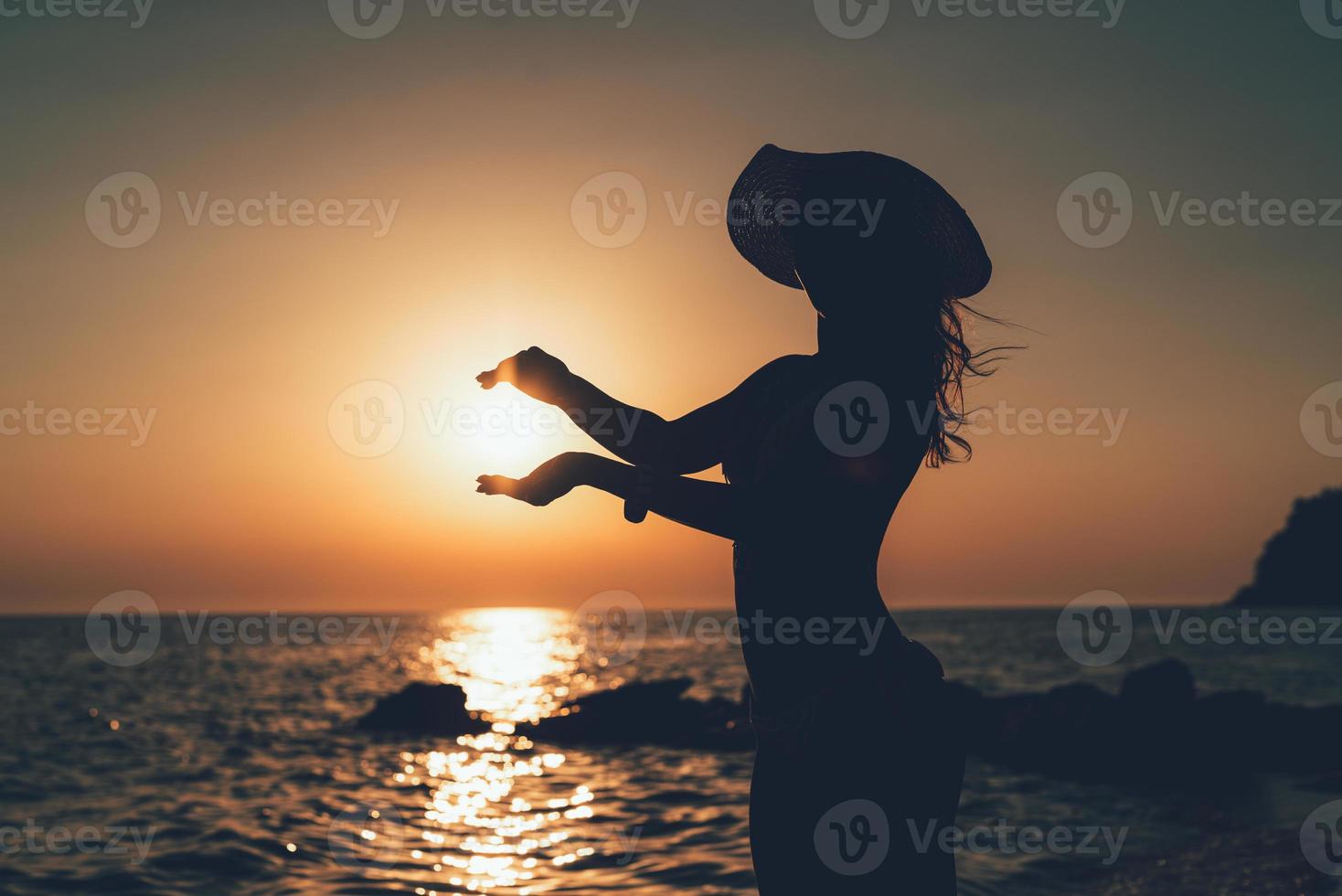 mujer joven sosteniendo el sol al atardecer foto