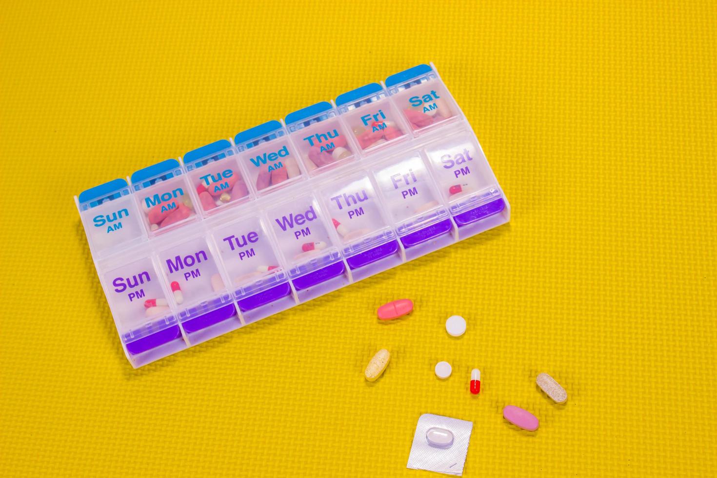 Weekly Pill Box Container On Patterned Yellow Background photo