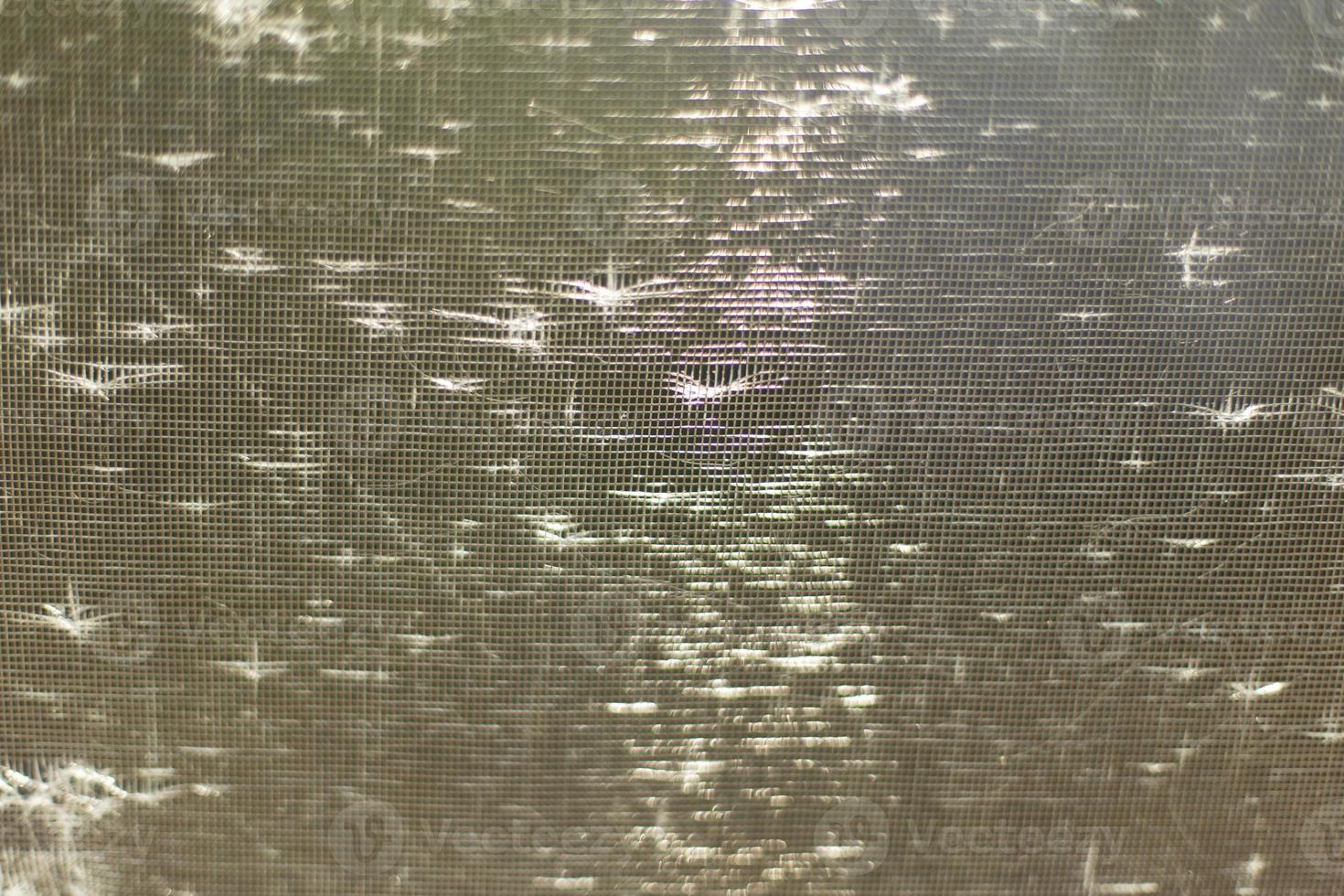 Sunlight on masked grid. Texture of bright rays. Glare on fine mosquito net. photo
