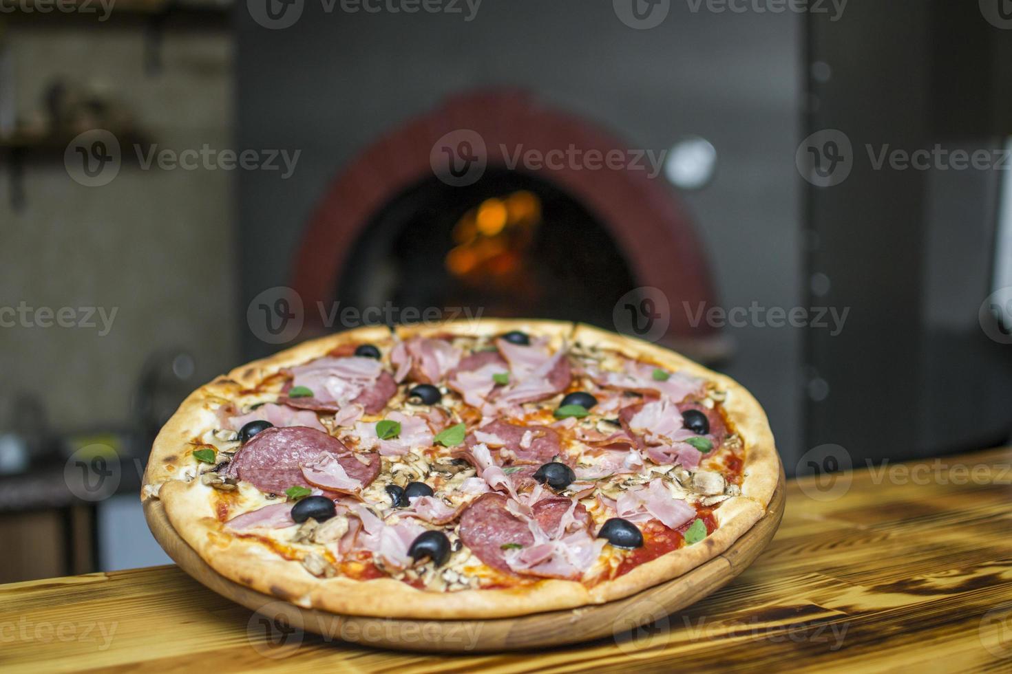 Pizza near the stone stove with fire. Background of a traditional pizzeria restaurant with a fire place. photo