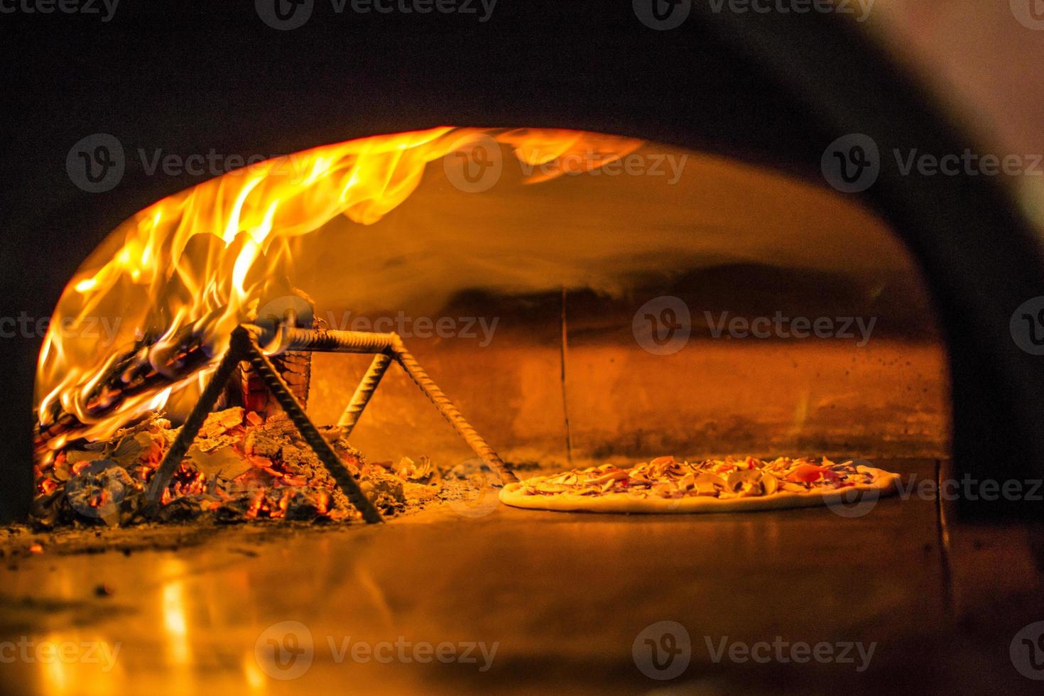 Pizza near the stone stove with fire. Background of a traditional pizzeria restaurant with a fire place. photo