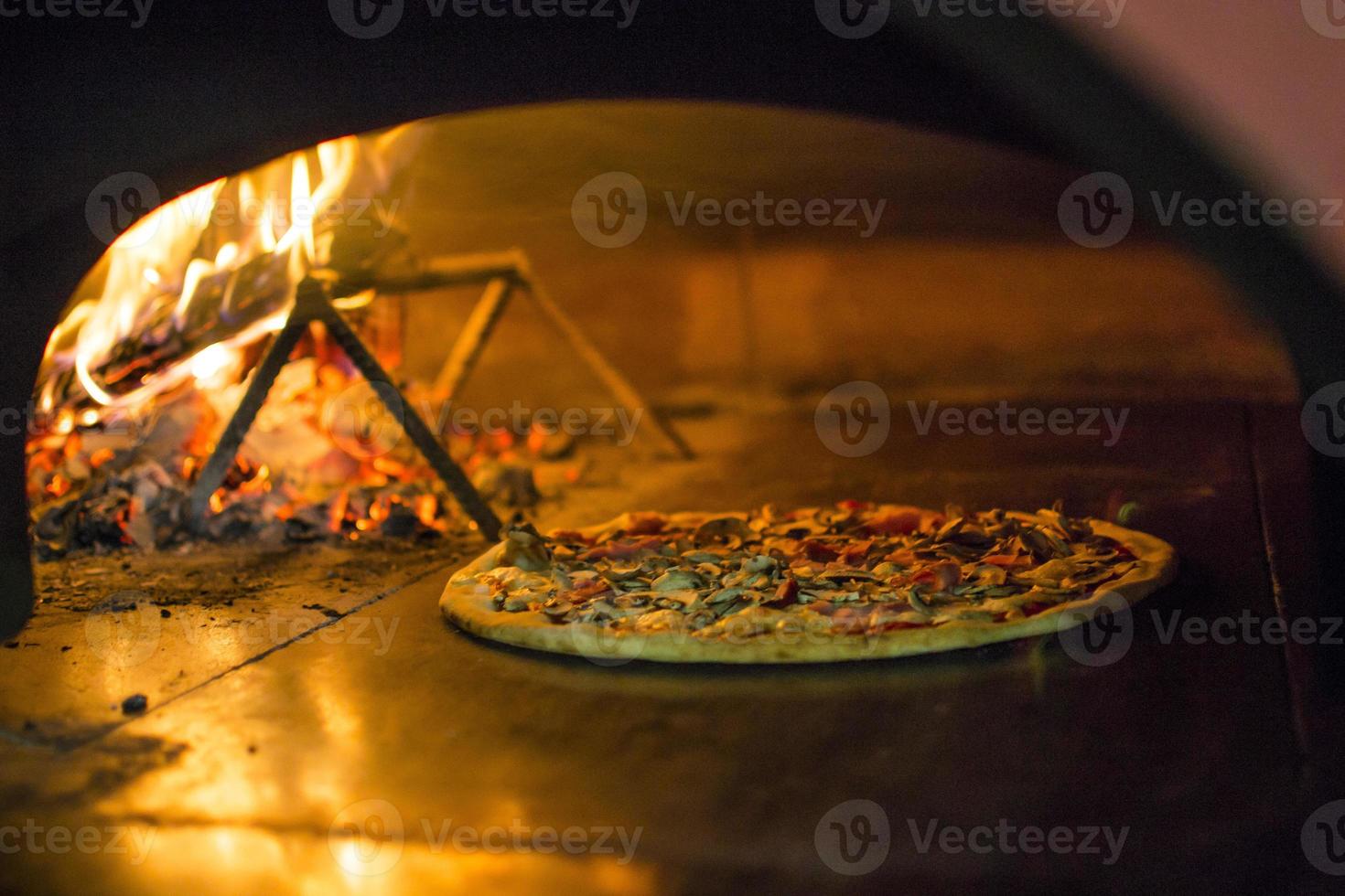 Pizza near the stone stove with fire. Background of a traditional pizzeria restaurant with a fire place. photo