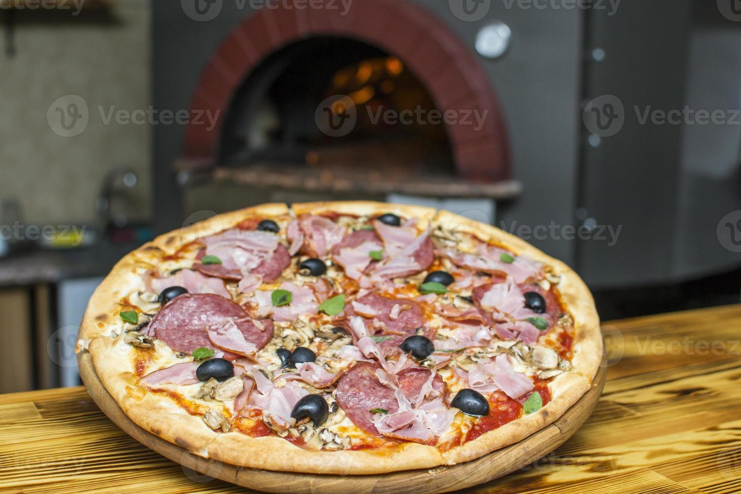 Pizza near the stone stove with fire. Background of a traditional pizzeria restaurant with a fire place. photo