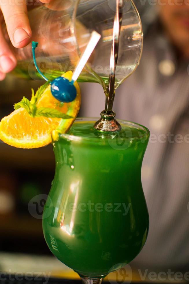 Bartender making refreshing coctail on a bar background. Dark moody style. Ice in tha glass photo