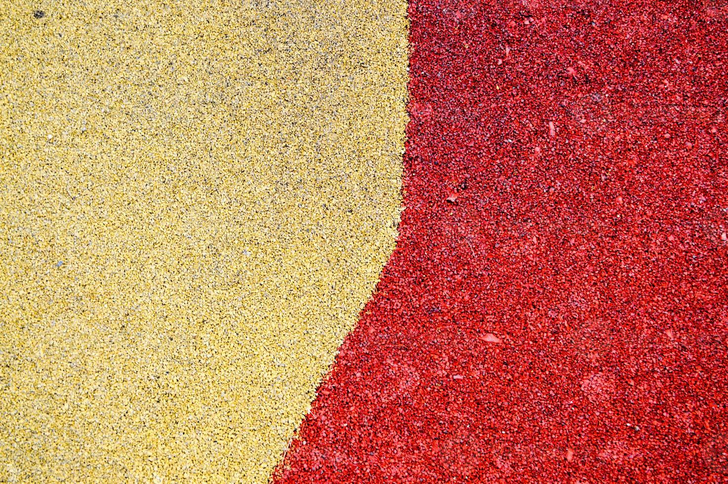 suelo de goma suave amarillo y rojo brillante seguro para deportes y entrenamiento o en el patio de recreo de los muchos pequeños guijarros redondos presionados. fondo, textura foto