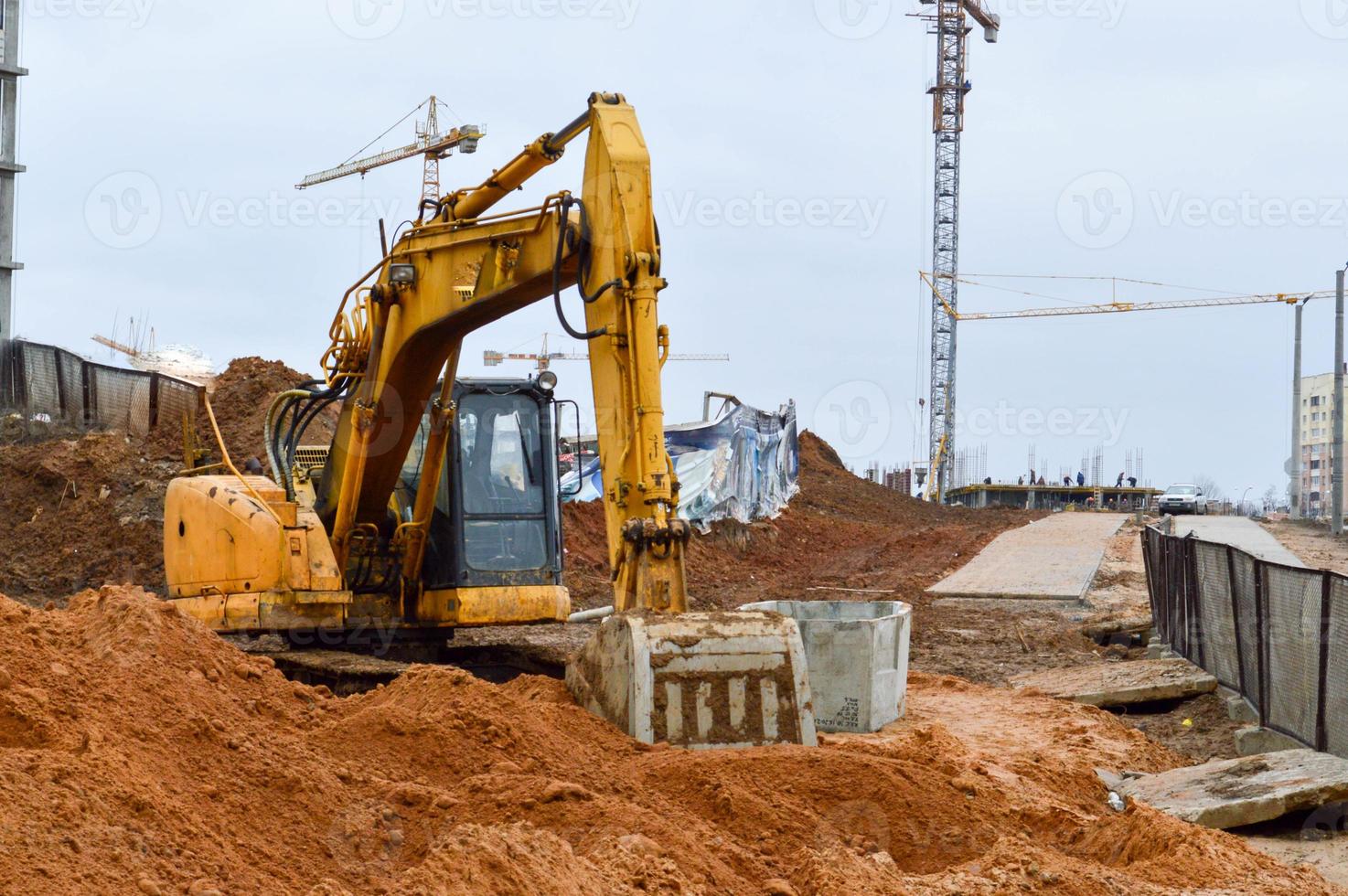 Big bright yellow powerful industrial heavy excavator tractor, bulldozer, specialized construction equipment for road repair during the construction of a new micro-district in a big city photo