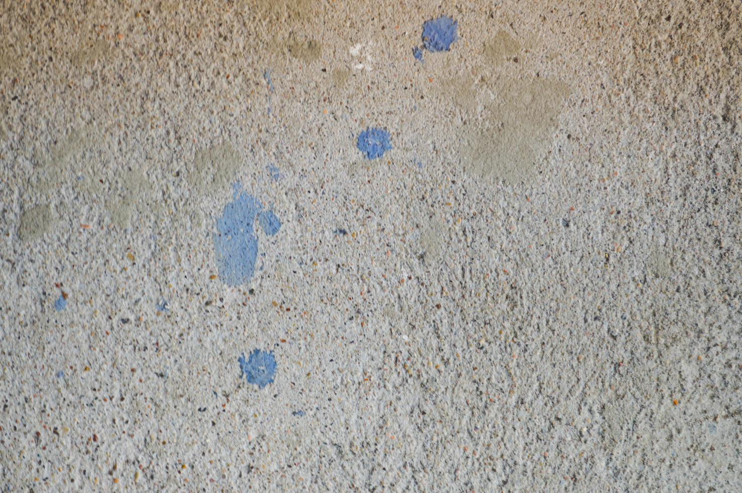 Wall of gray solid, shaggy, embossed building concrete with spots of blue paint. Texture, background photo