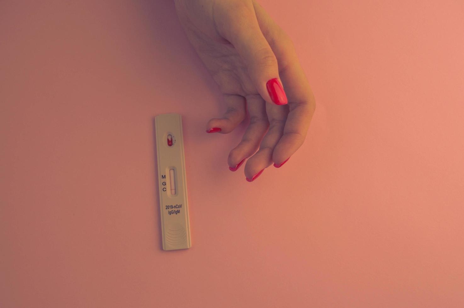 chica con manicura roja brillante haciendo una prueba de coronavirus. un análisis de sangre para determinar la infección en el hogar. prueba rápida express, diagnóstico de salud foto