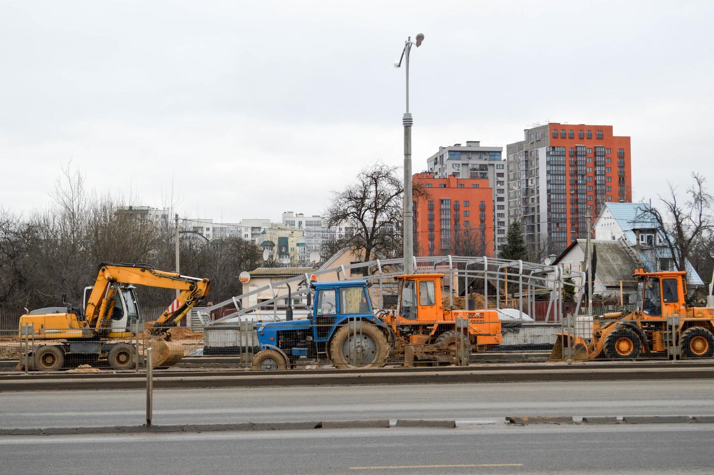 Many powerful industrial heavy specialized construction equipment of tractor excavators and bulldozers make road repairs during the construction of a new micro-district in a big city photo