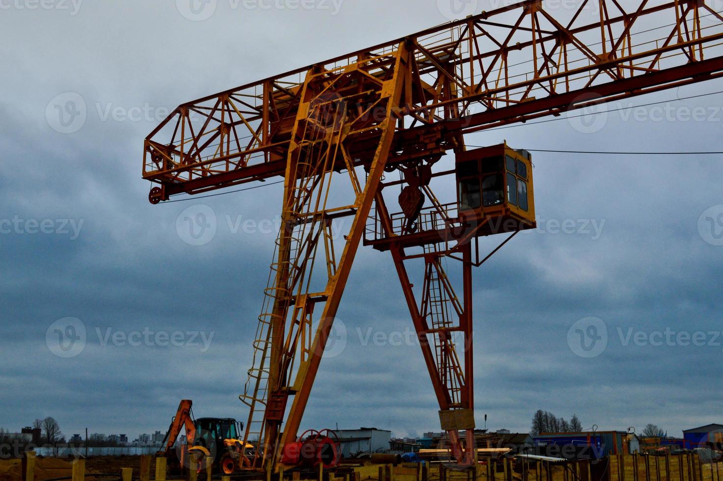 High heavy yellow metal iron load-bearing construction stationary industrial powerful gantry crane of bridge type on supports for lifting cargo on a modern construction site of buildings and houses photo