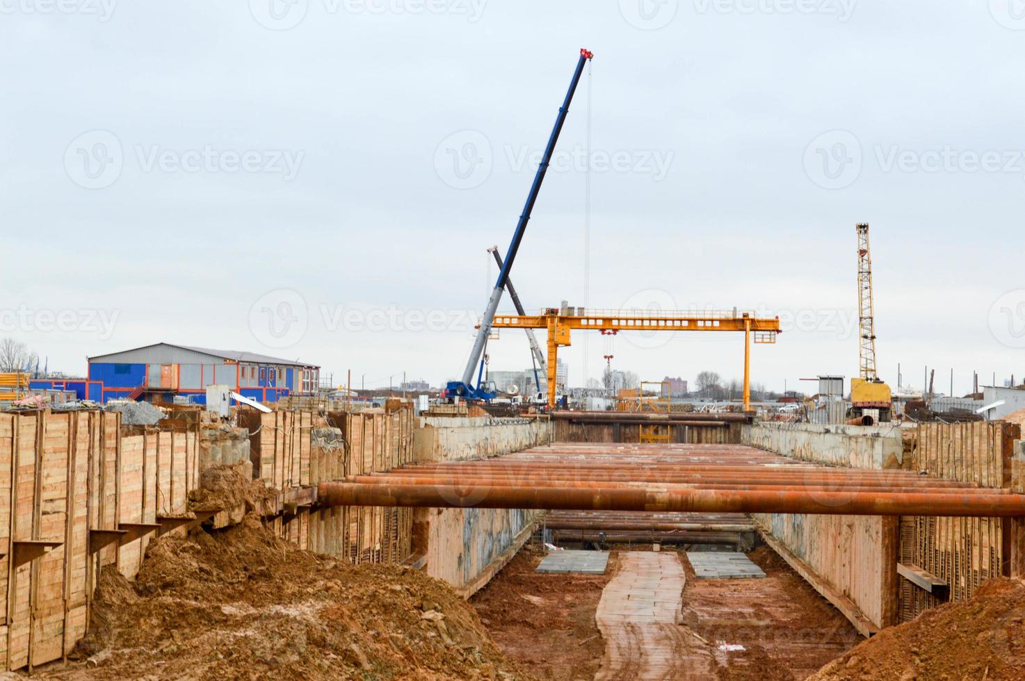 A large huge ditch pit tunnel with reinforcing structures from thick iron pipes of beams and structures at the construction site of the underground metro station line photo