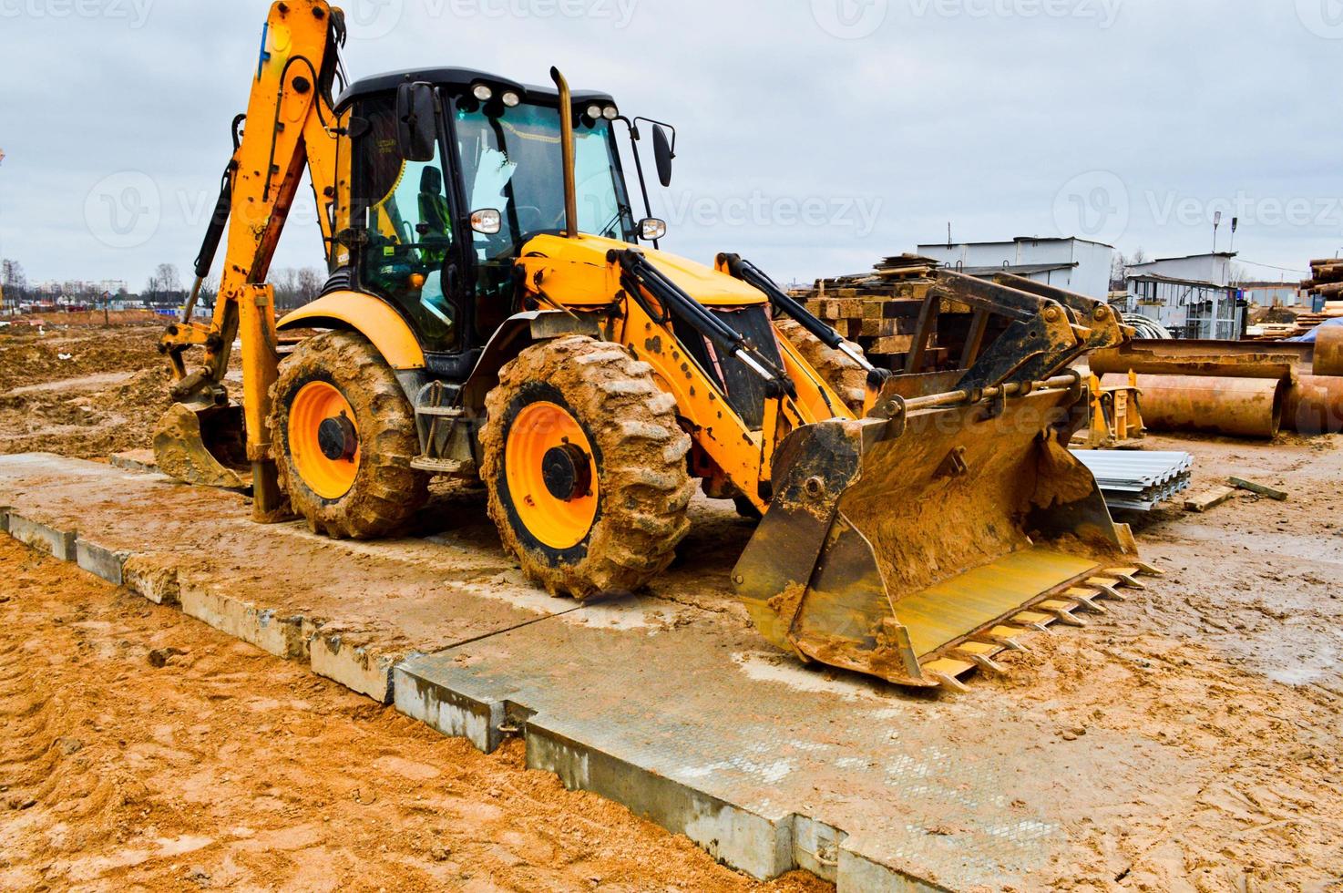 Big bright yellow powerful industrial heavy excavator tractor, bulldozer, specialized construction equipment for road repair during the construction of a new micro-district in a big city photo