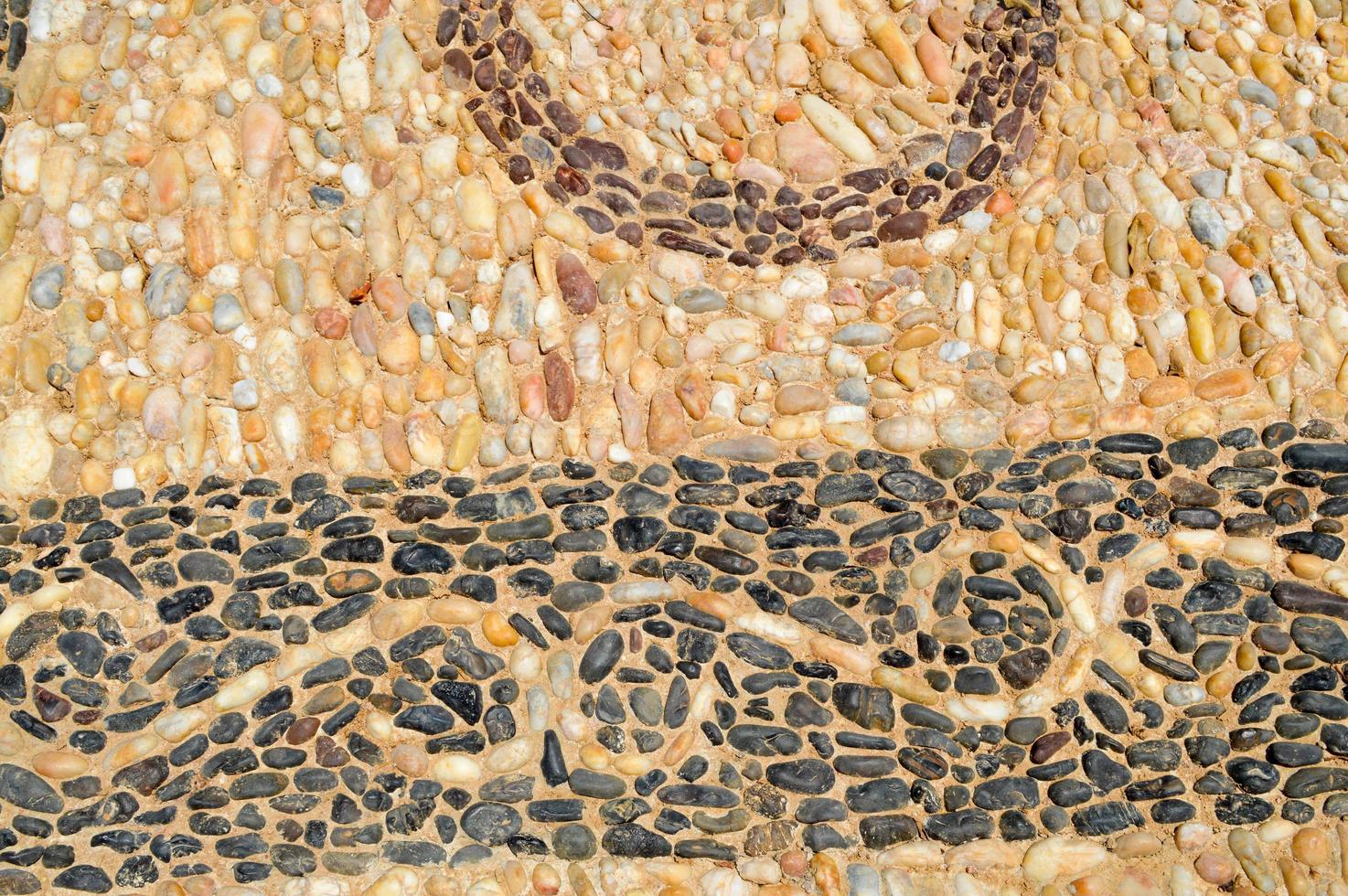 The texture of the stone wall, the road from small round and oval stones with abstract lines laid out patterns of sandy seams of natural old yellow black brown. The background photo