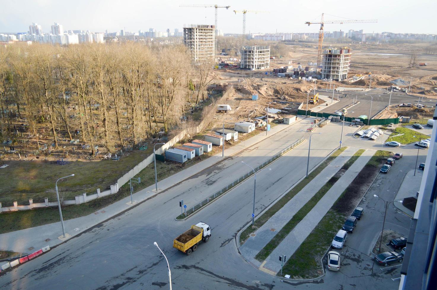 A large dump truck rides to a construction site and carries sand along an asphalt road. View from above photo