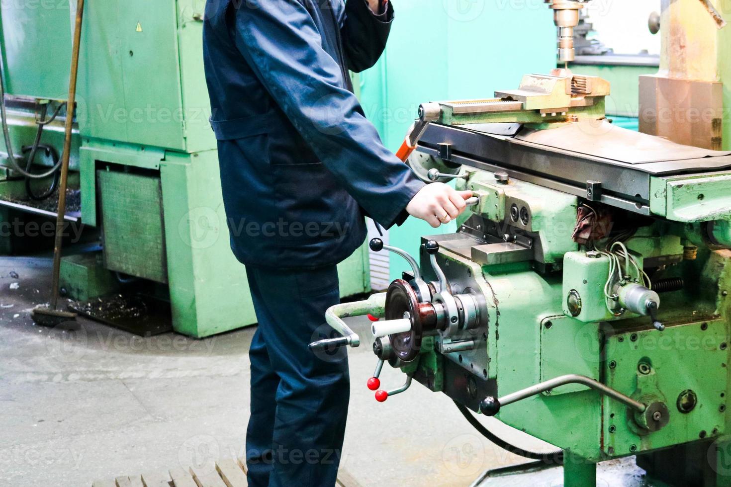 un trabajador masculino trabaja en un torno de cerrajería de hierro metálico más grande, equipo para reparaciones, trabajo de metal en un taller en una planta metalúrgica en una producción de reparación foto