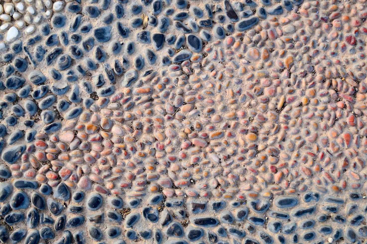 The texture of the stone wall, the road from small round and oval stones with abstract lines laid out patterns of sandy seams of natural old yellow black brown. The background photo