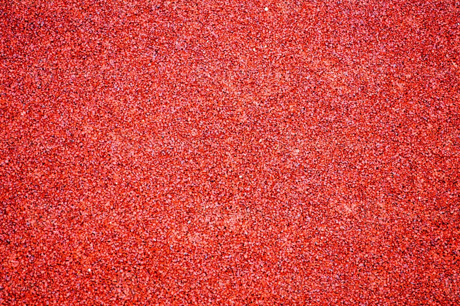 Red bright soft rubber flooring safe for sports and workout or on the playground from the many small round pebbles pressed. Background, texture photo