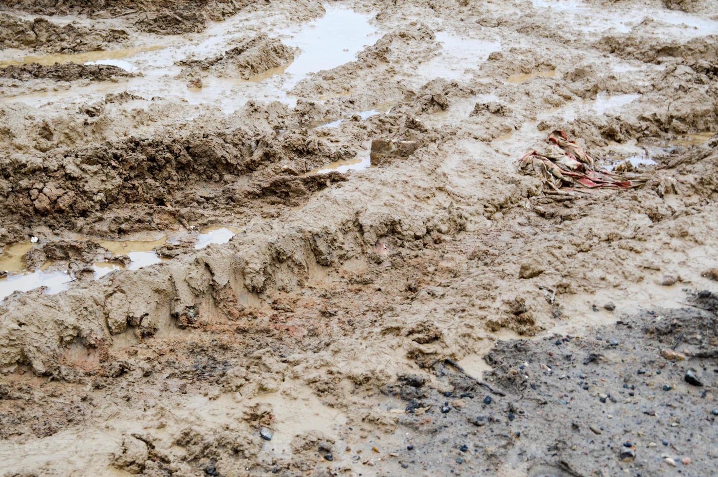 Texture of a dirty bad dirt road dirt road with puddles and clay drying mud with cracks and ruts. Off-road. The background photo
