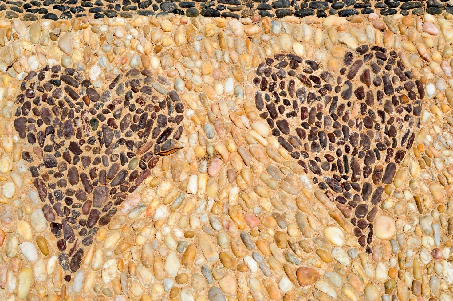 The texture of the stone wall, the road from small round and oval stones with abstracted lines of patterns of two hearts sandy seams of natural old yellow black brown. The background photo