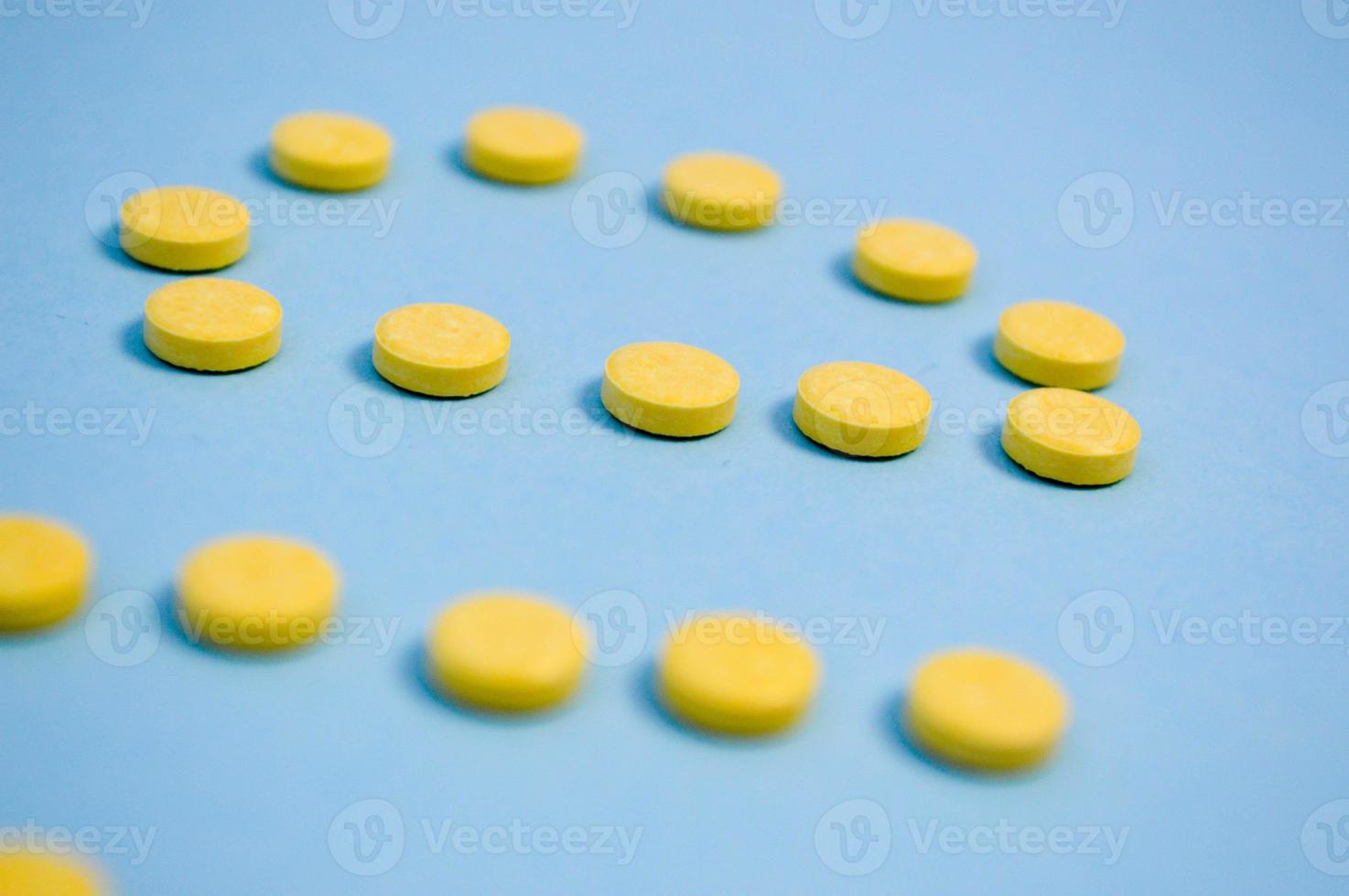 Yellow round medical pharmaceutical for the treatment of diseases and the killing of microbes and viruses pills and vitamins medicines for coronavirus on a blue background photo