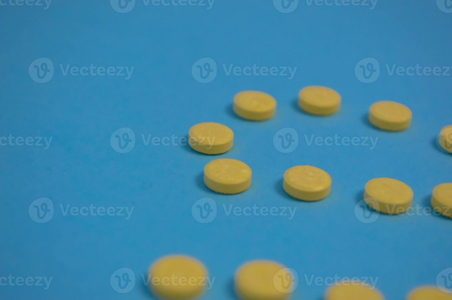 Yellow round medical pharmaceutical for the treatment of diseases and the killing of microbes and viruses pills and vitamins medicines for coronavirus on a blue background photo