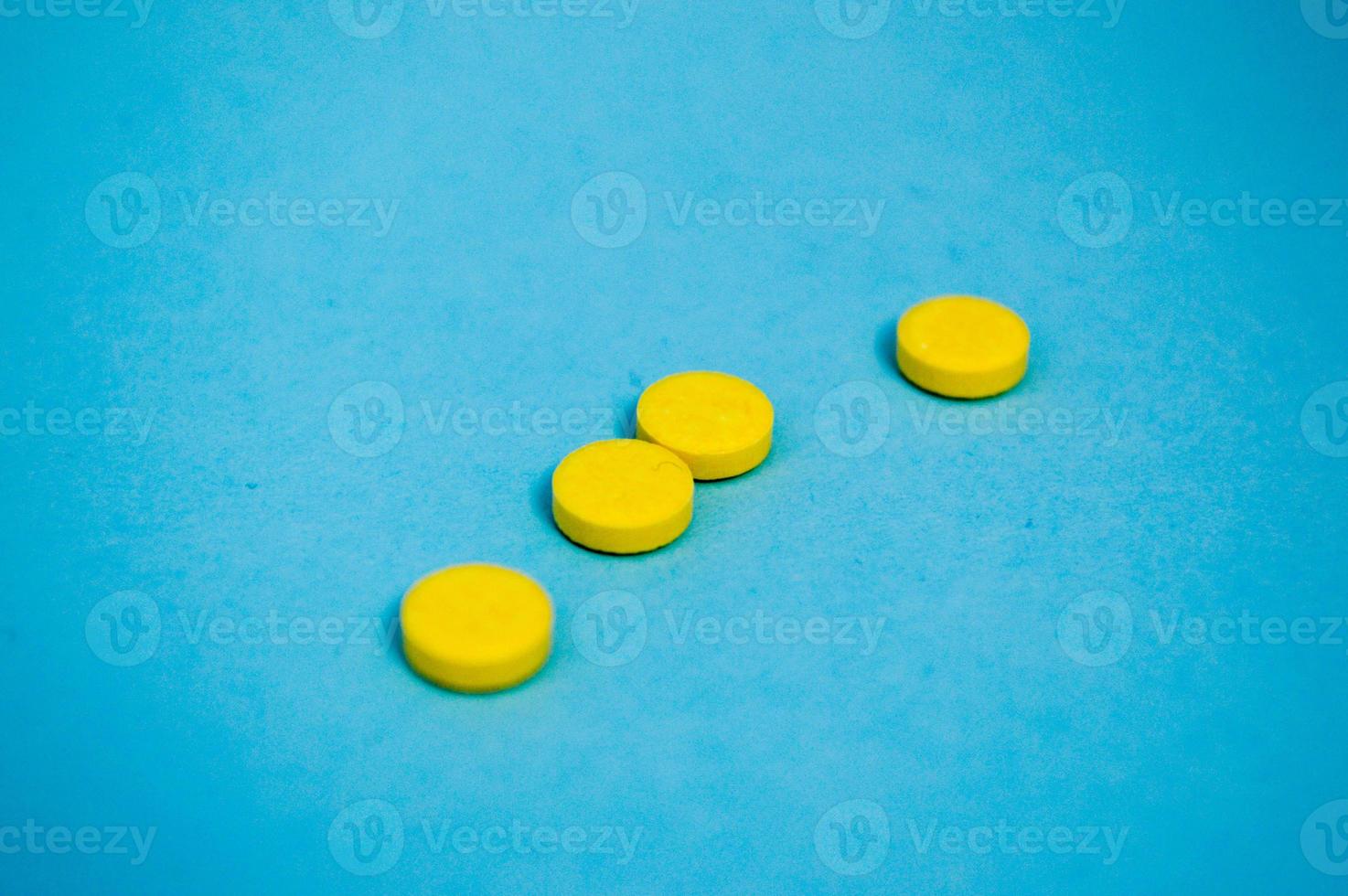 Yellow round medical pharmaceutical for the treatment of diseases and the killing of microbes and viruses pills and vitamins medicines for coronavirus on a blue background photo