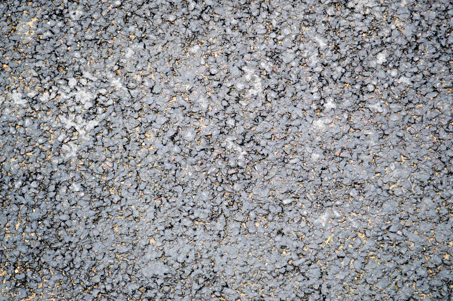 Gray asphalt road with small pebbles and cracks. Texture, background photo