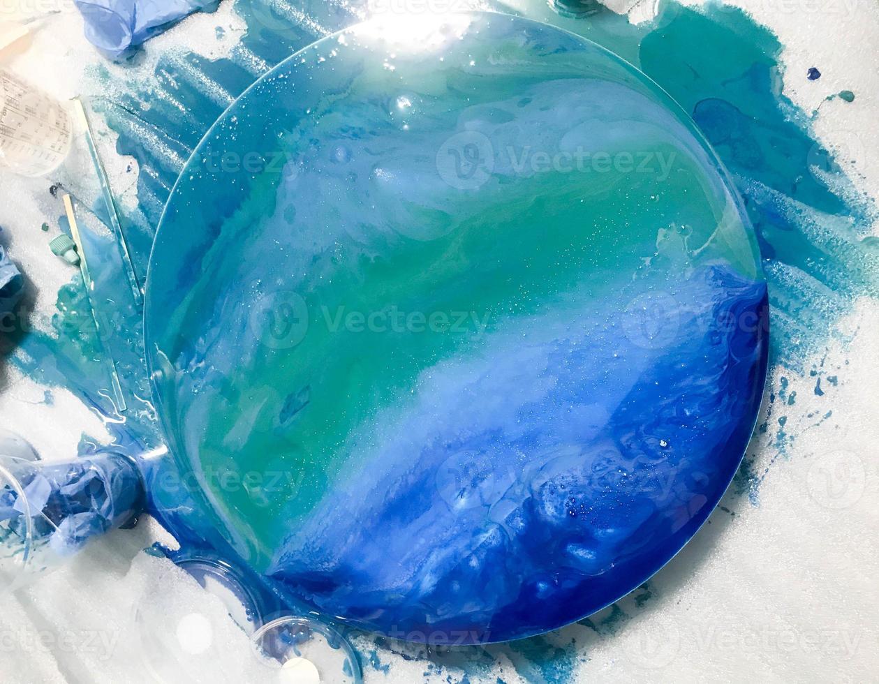 abstract unusual painting depicting the ocean with an epoxy painting technique to create artworks. picture on a colored blue background with bubbles. white lens flare in the shape of the sun photo