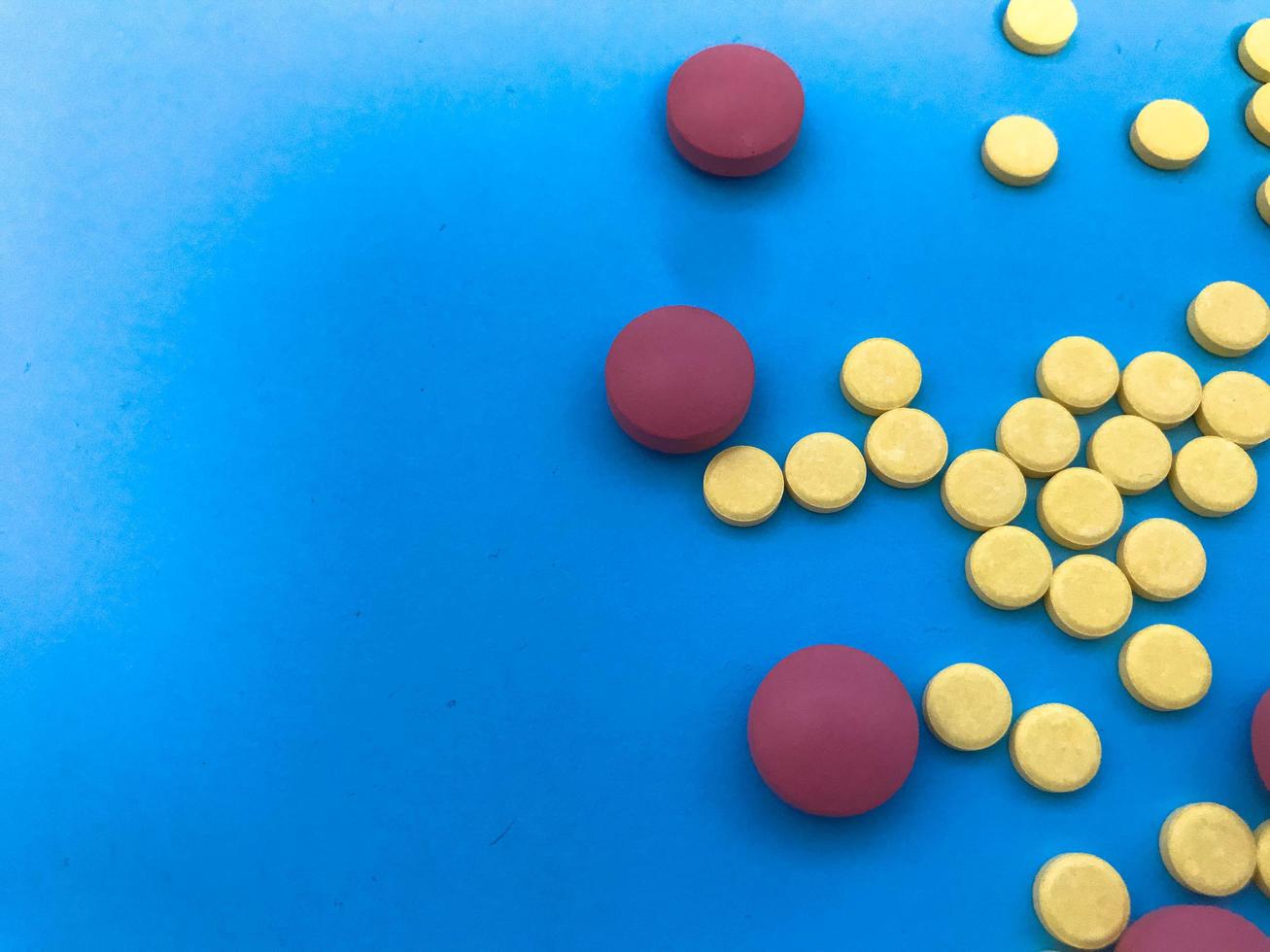 colored pink, yellow pills volumetric and round in shape on a blue matte and paper background. health medications. herbal medicines. medical background photo