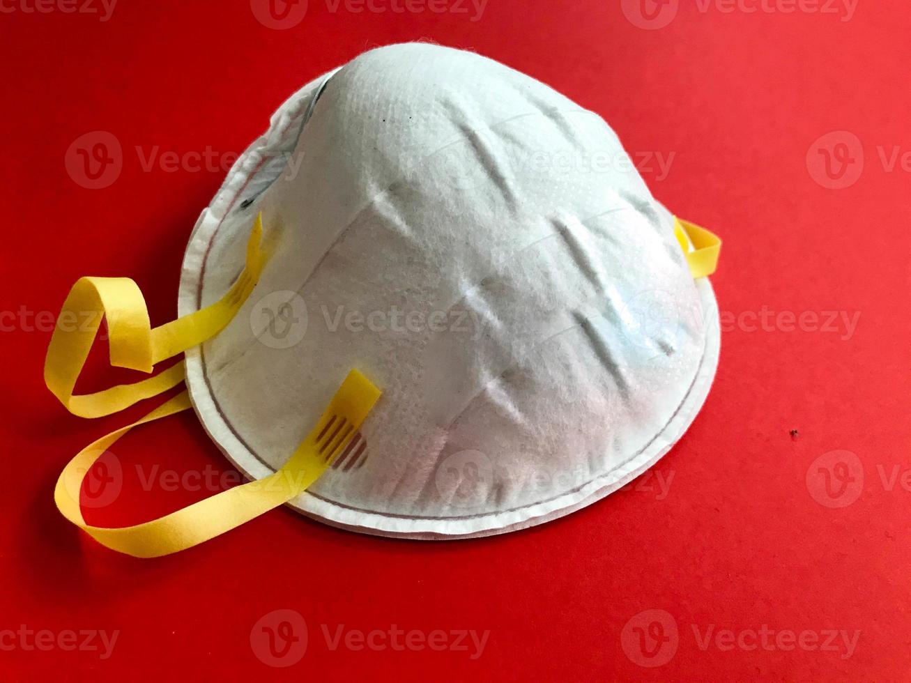 Disposable white protective medical mask for protection against dangerous deadly diseases of microbes and viruses with coronavirus covid-19 on a red background photo