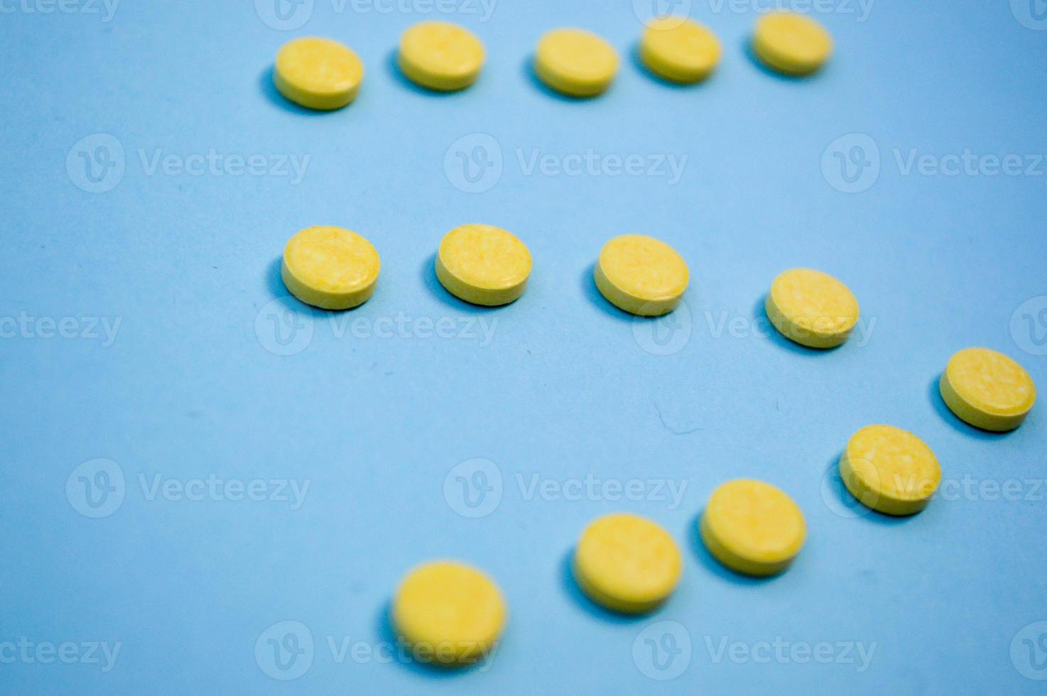 Yellow round medical pharmaceutical for the treatment of diseases and the killing of microbes and viruses pills and vitamins medicines for coronavirus on a blue background photo
