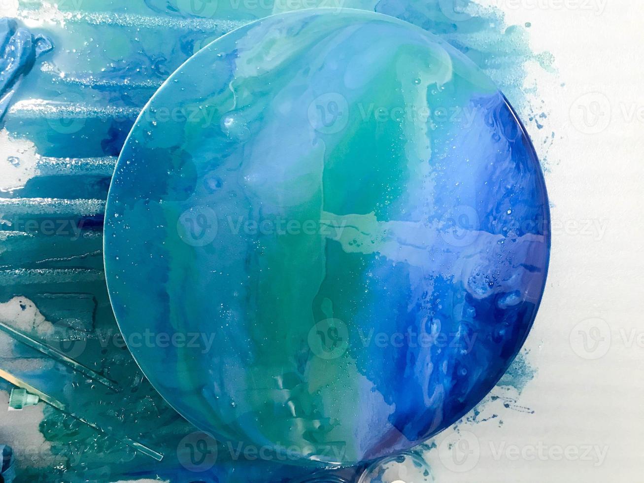 round glossy picture with the image of the sea surface of blue with bubbles using the technique of drawing with epoxy resin. a picture with castings in the author's technique with highlights photo
