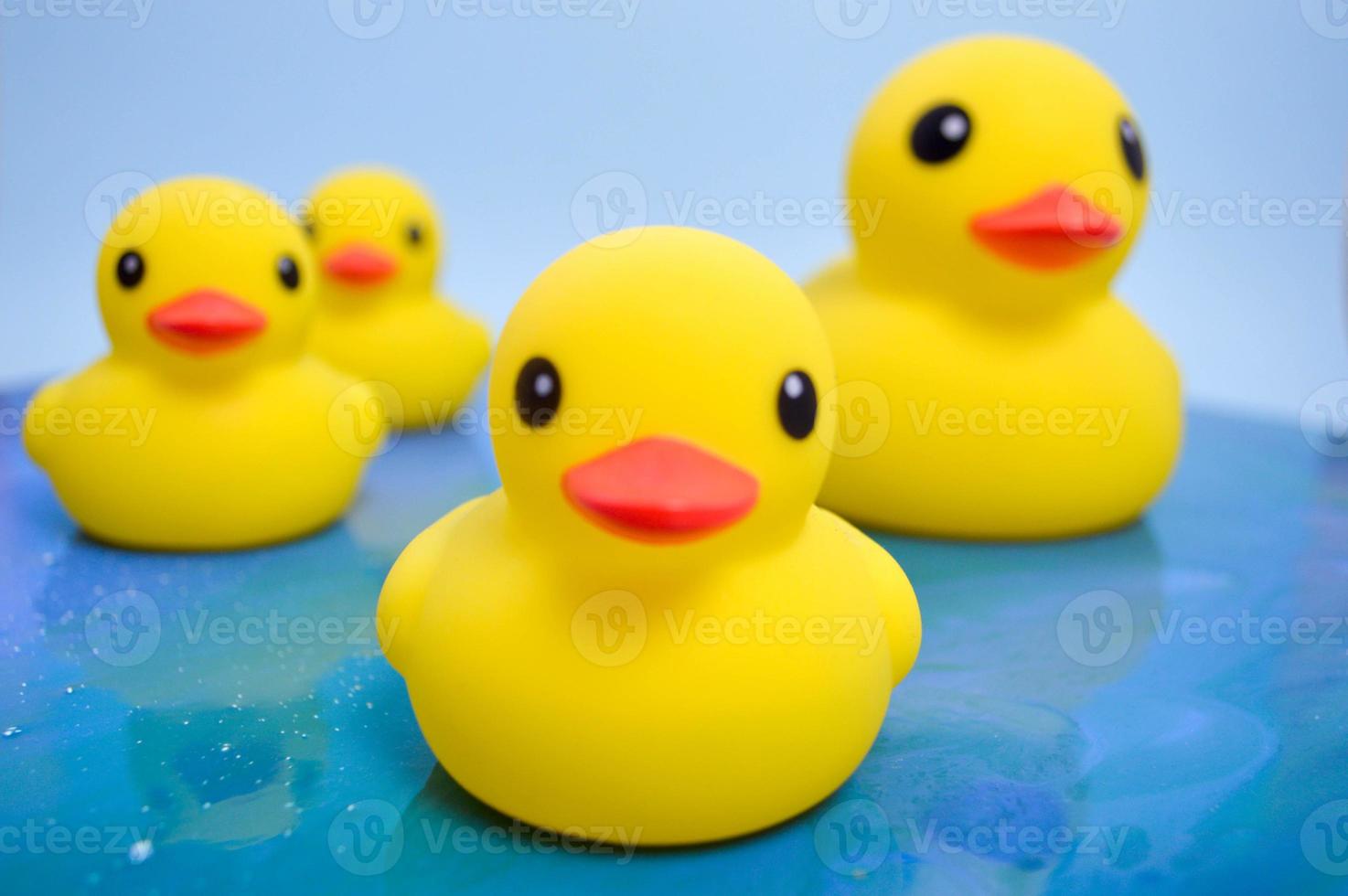 a family of ducks floating on an artificial reservoir of epoxy resin due to environmental pollution. yellow rubber duck sits on the water using the fluid art technique photo