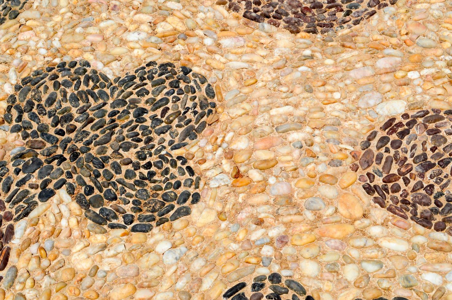 The texture of the stone wall, the road from small round and oval stones with abstract lines laid out patterns of sandy seams of natural old yellow black brown. The background photo