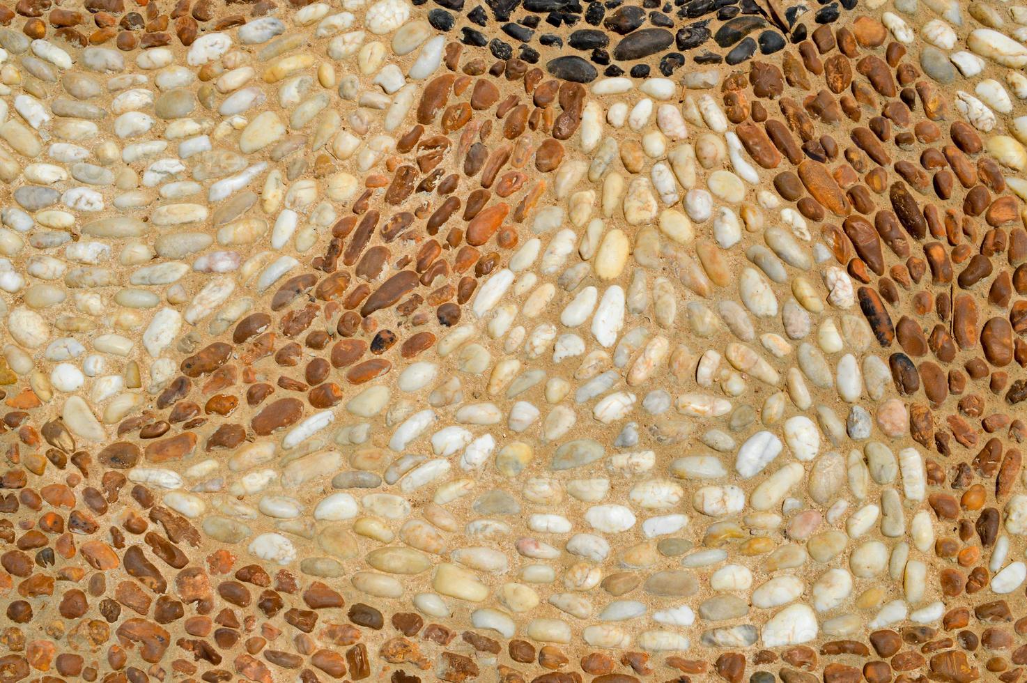 The texture of the stone wall, the road from small round and oval stones with abstract lines laid out patterns of sandy seams of natural old yellow black brown. The background photo