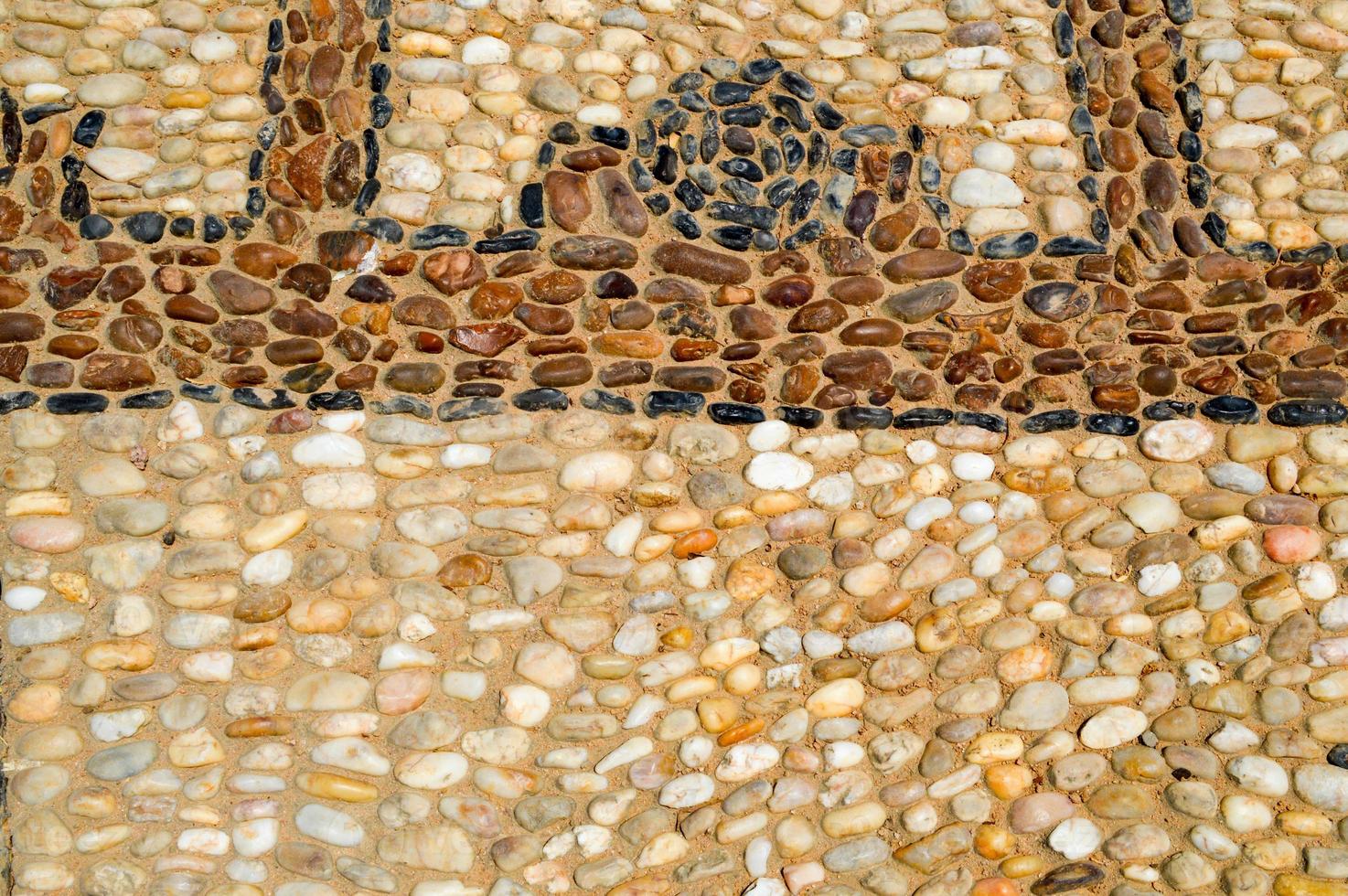 The texture of the stone wall, the road from small round and oval stones with abstract lines laid out patterns of sandy seams of natural old yellow black brown. The background photo
