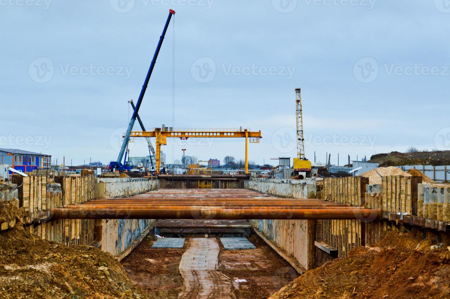 A large huge ditch pit tunnel with reinforcing structures from thick iron pipes of beams and structures at the construction site of the underground metro station line photo